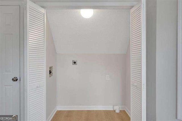 laundry area featuring electric dryer hookup, baseboards, and light wood-style floors