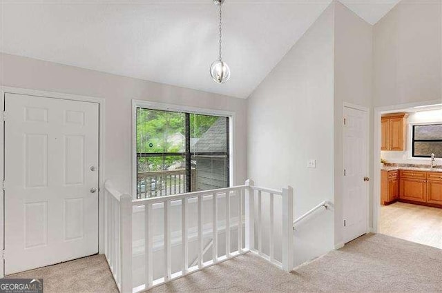 entryway with vaulted ceiling, an inviting chandelier, and light carpet