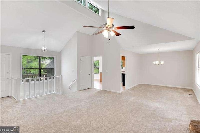 unfurnished living room with baseboards, high vaulted ceiling, light colored carpet, and ceiling fan with notable chandelier