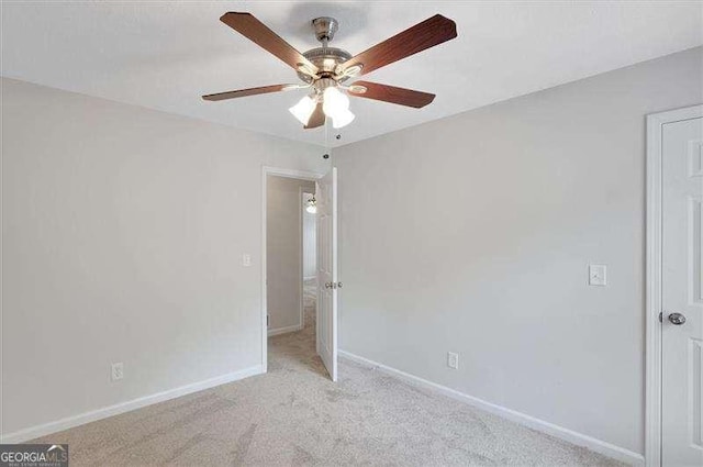 empty room with light colored carpet, baseboards, and a ceiling fan