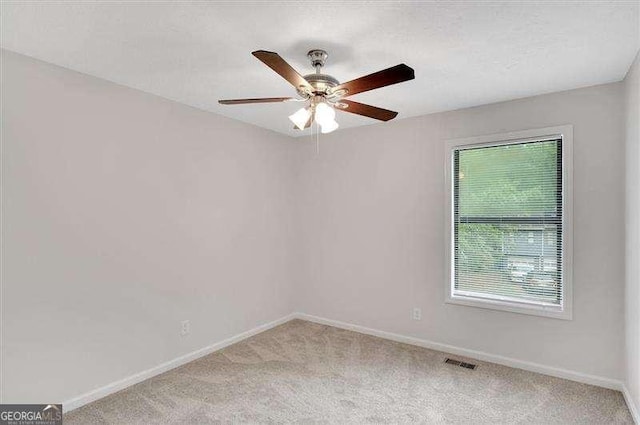 unfurnished room featuring light colored carpet, visible vents, baseboards, and a ceiling fan