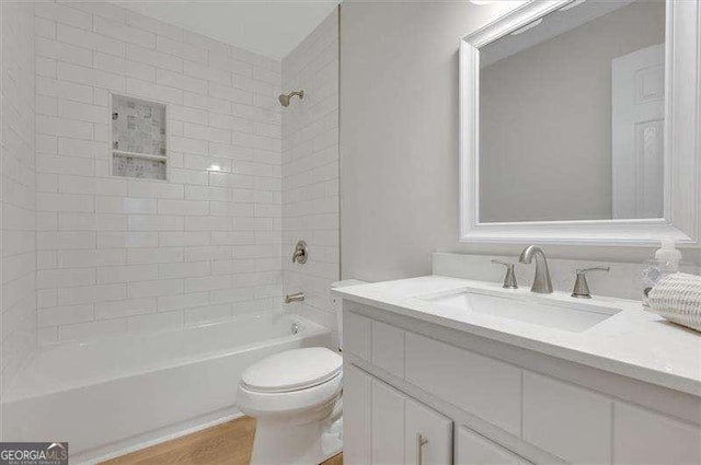 bathroom with vanity, toilet, wood finished floors, and shower / bath combination