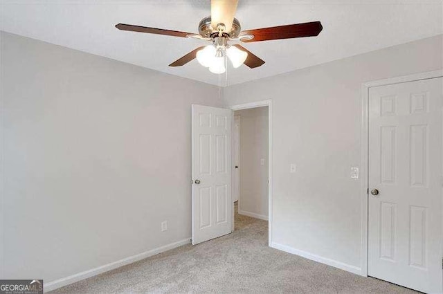 unfurnished bedroom featuring light carpet, baseboards, and a ceiling fan