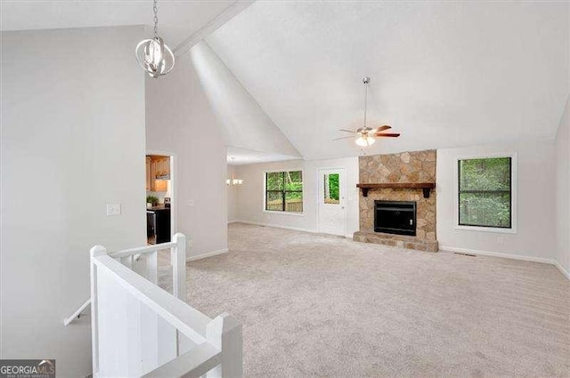 unfurnished living room featuring ceiling fan with notable chandelier, high vaulted ceiling, a fireplace, carpet floors, and baseboards