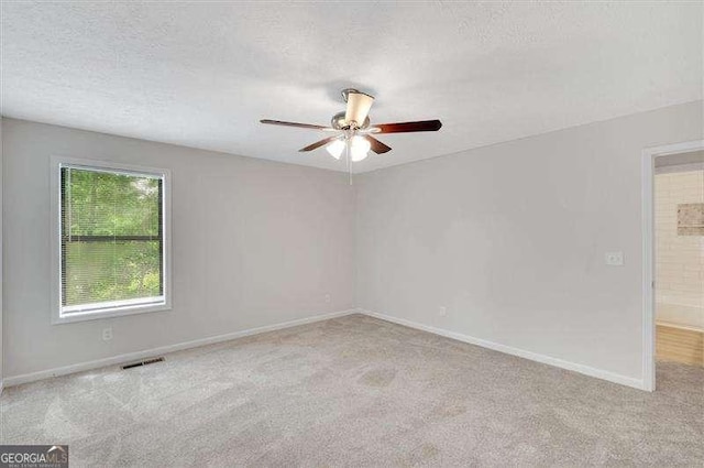 carpeted empty room with a ceiling fan, baseboards, visible vents, and a textured ceiling