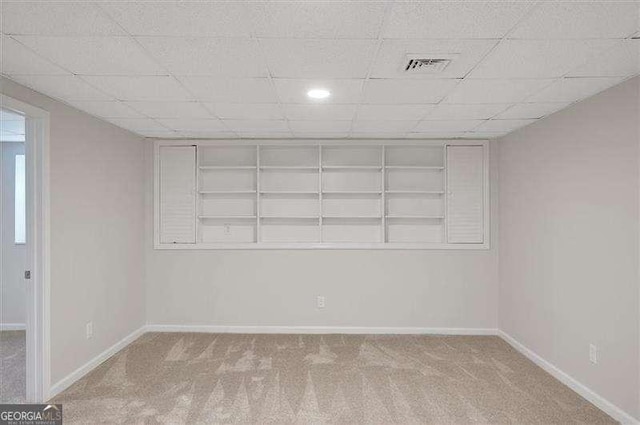 unfurnished room featuring carpet, visible vents, baseboards, and a paneled ceiling