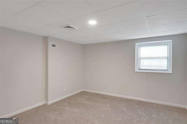 carpeted empty room featuring a drop ceiling, visible vents, and baseboards