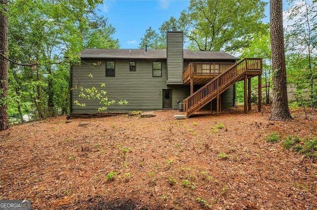 rear view of property featuring stairs, a chimney, and a deck