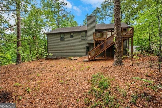 back of property featuring a chimney, stairs, and a deck