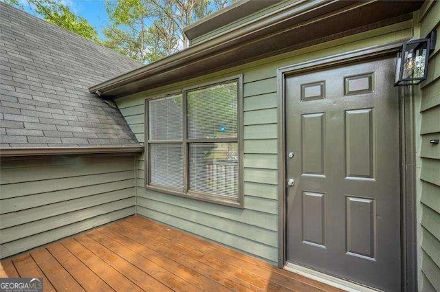 entrance to property featuring roof with shingles