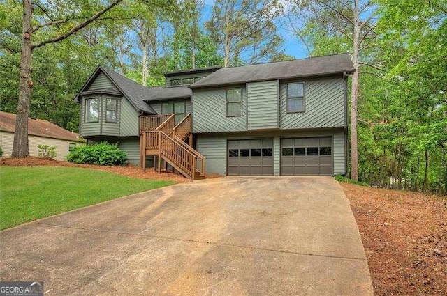 raised ranch with a front lawn, driveway, a garage, and stairway