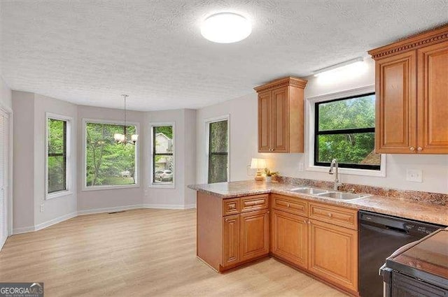 kitchen with a peninsula, a sink, black dishwasher, a textured ceiling, and light wood-style floors