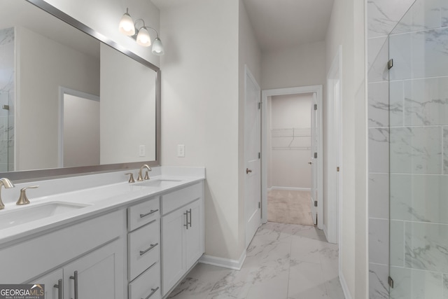 full bathroom featuring double vanity, a sink, a walk in closet, baseboards, and marble finish floor