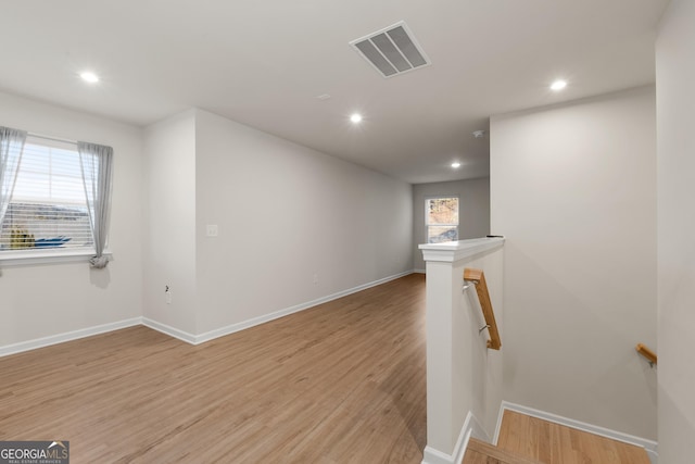 stairway with visible vents, wood finished floors, and recessed lighting