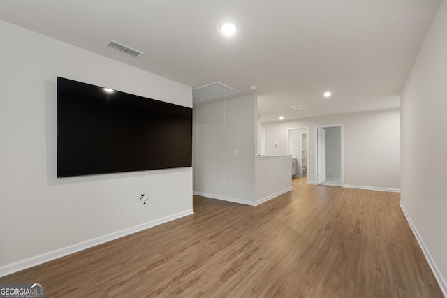 unfurnished living room featuring light wood-style flooring, attic access, visible vents, baseboards, and recessed lighting