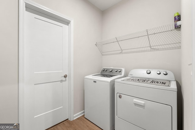 washroom with laundry area, light wood-style floors, baseboards, and washing machine and dryer