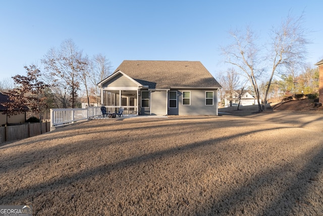 rear view of house featuring a sunroom, a shingled roof, a lawn, and ceiling fan