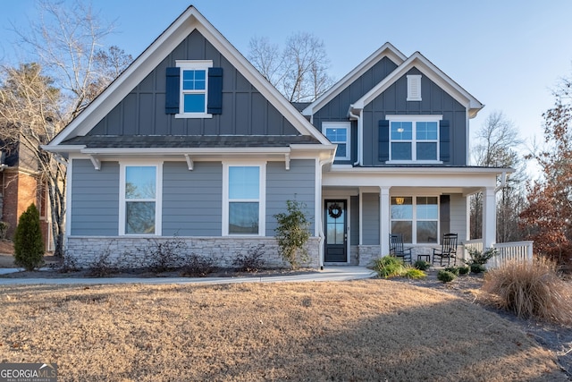 craftsman-style house featuring covered porch, board and batten siding, and stone siding