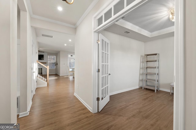 hallway with crown molding, stairs, visible vents, and wood finished floors