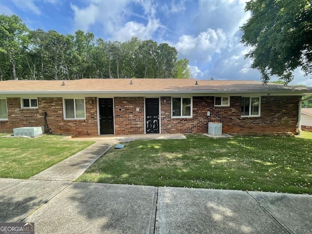 view of front facade with central AC, a front yard, and brick siding