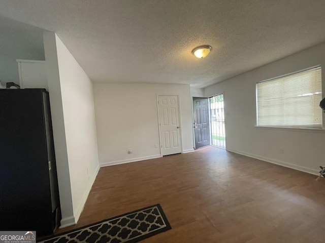 unfurnished room featuring a textured ceiling, baseboards, and wood finished floors