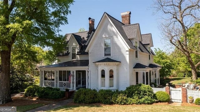 exterior space with a chimney, fence, a sunroom, a shingled roof, and a gate
