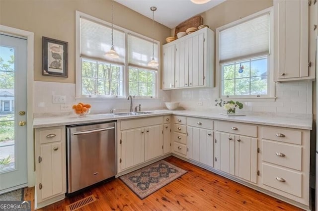 kitchen with a sink, tasteful backsplash, dishwasher, light countertops, and light wood-style floors