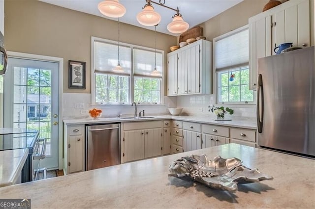 kitchen with a sink, decorative light fixtures, backsplash, light countertops, and appliances with stainless steel finishes