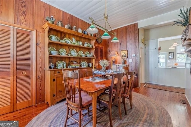dining space featuring wooden walls, wood ceiling, and hardwood / wood-style flooring