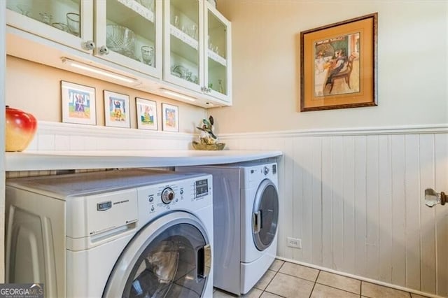 washroom featuring separate washer and dryer, cabinet space, wainscoting, and light tile patterned flooring