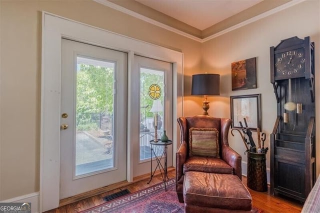 living area featuring ornamental molding, visible vents, and wood finished floors