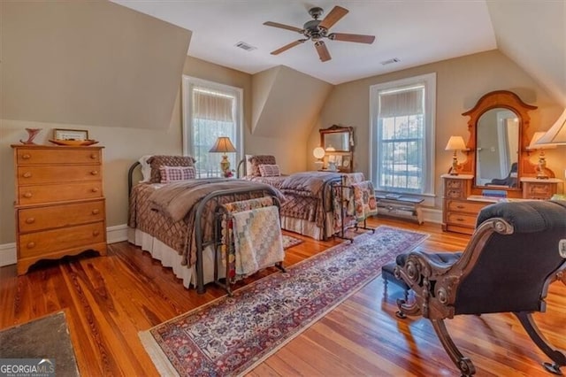 bedroom featuring lofted ceiling, multiple windows, visible vents, and wood finished floors