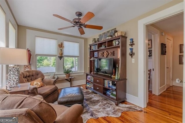 living room with ceiling fan, baseboards, and wood finished floors