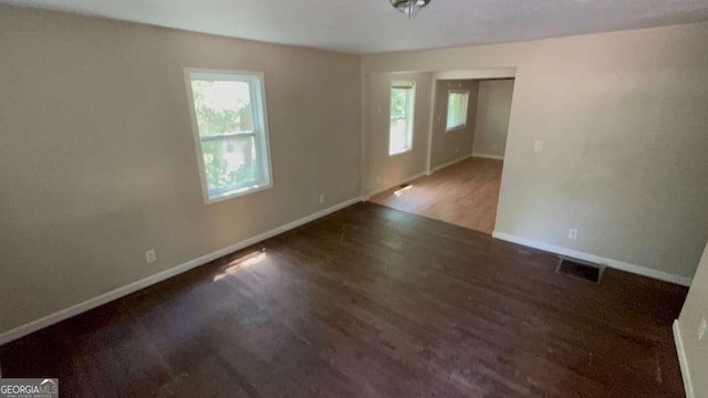 unfurnished room featuring wood finished floors, visible vents, and baseboards
