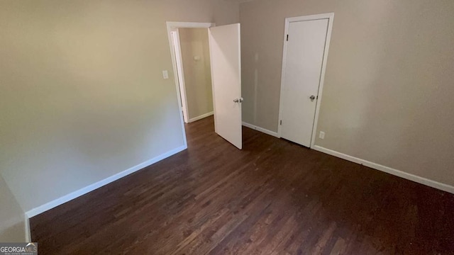 spare room with baseboards and dark wood-style floors