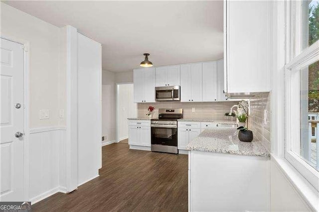 kitchen featuring a sink, dark wood-type flooring, backsplash, white cabinets, and appliances with stainless steel finishes