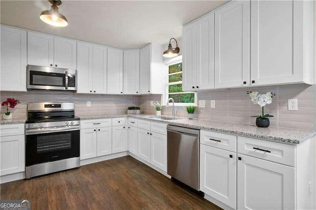 kitchen with white cabinetry, stainless steel appliances, decorative backsplash, and a sink