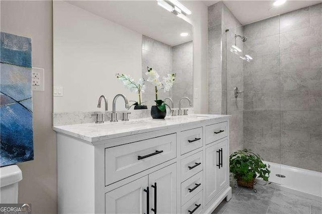 full bath with a sink, double vanity, and a tile shower
