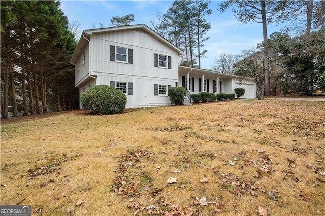 view of front of home with covered porch, a garage, and a front lawn