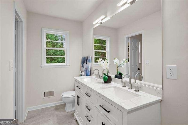 full bath featuring double vanity, toilet, visible vents, and a sink