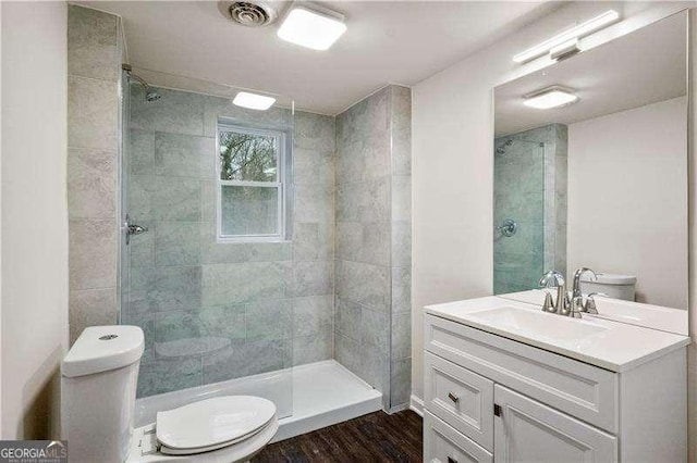 full bath with toilet, tiled shower, and visible vents