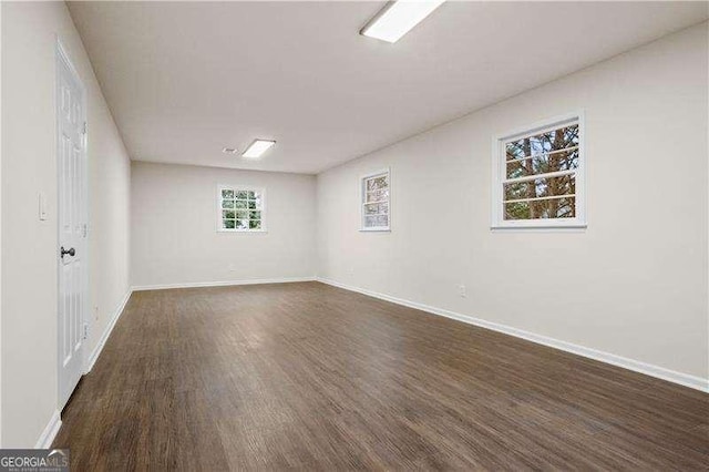unfurnished room with baseboards and dark wood finished floors