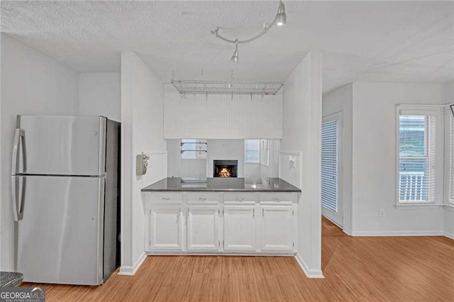 4440 Coventry Ct NE, Roswell, GA 30075 - kitchen featuring light wood-style flooring, freestanding refrigerator, dark countertops, white cabinets, and baseboards
