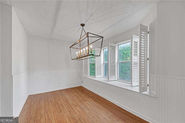 4440 Coventry Ct NE, Roswell, GA 30075 - unfurnished dining area with a wainscoted wall, a textured ceiling, wood finished floors, and an inviting chandelier