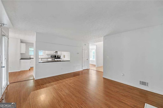 4440 Coventry Ct NE, Roswell, GA 30075 - unfurnished living room with visible vents, wood finished floors, and a healthy amount of sunlight