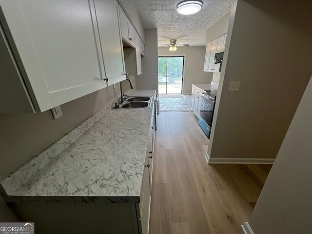 1466 Pine Log Rd NE Unit A, Conyers, GA 30012 - kitchen featuring light wood finished floors, a ceiling fan, a sink, white cabinets, and range with electric stovetop