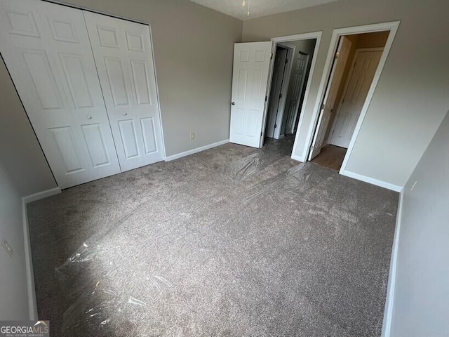 1466 Pine Log Rd NE Unit A, Conyers, GA 30012 - unfurnished bedroom featuring dark colored carpet, baseboards, and a closet