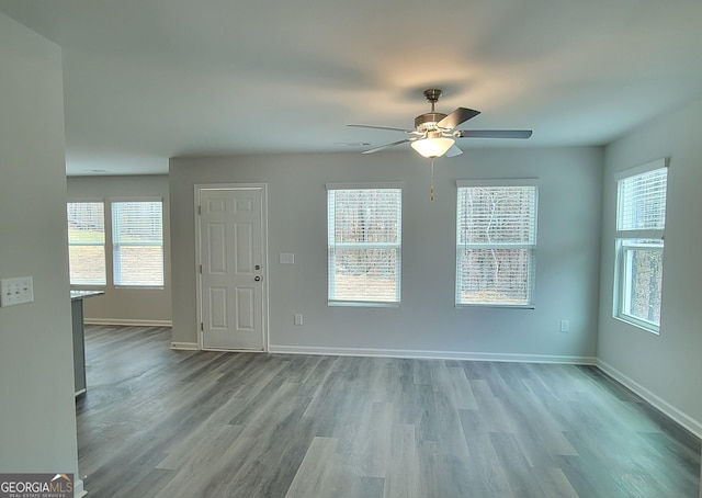 unfurnished living room featuring baseboards, wood finished floors, and a ceiling fan