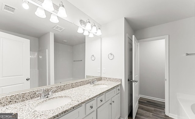 bathroom with a tub, visible vents, a sink, and wood finished floors