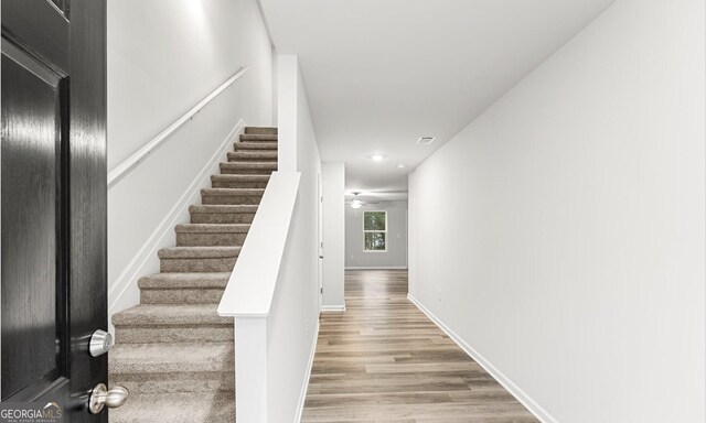 stairs featuring wood finished floors, a ceiling fan, visible vents, baseboards, and recessed lighting